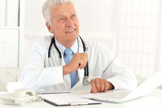 Foto retrato de un médico que trabaja con una laptop en su oficina