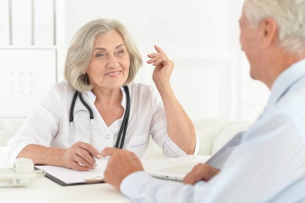 Retrato de médico senior hablar con paciente anciano