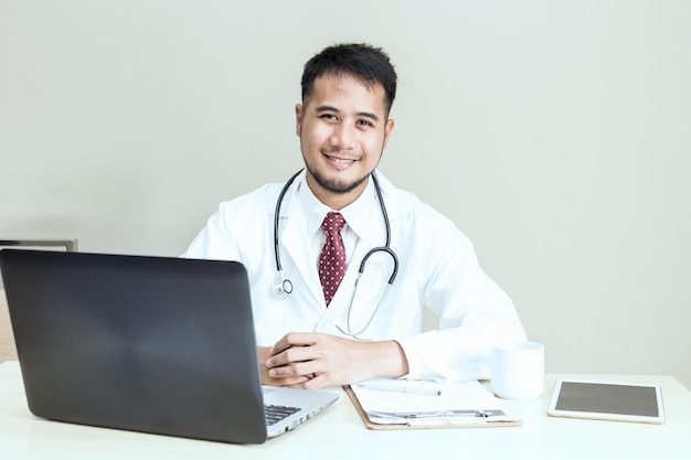 Retrato de un médico sentado en una mesa contra la pared