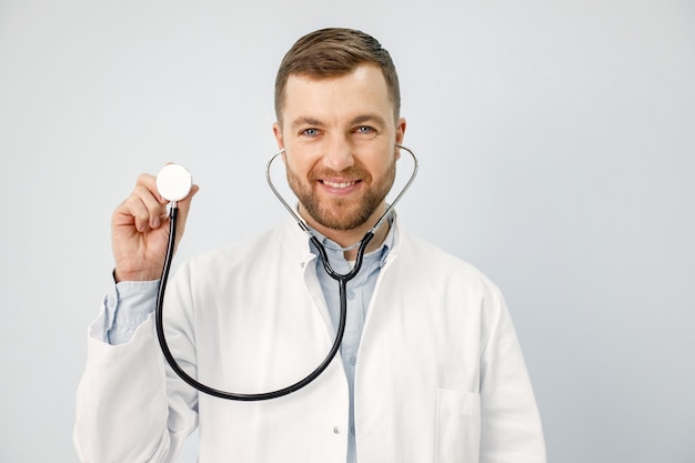 Retrato de un médico de sexo masculino que mira la cámara que sostiene un estetoscopio