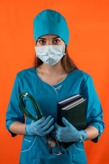 Foto retrato de un médico sonriente y alegre en uniforme blanco de pie con los brazos cruzados en un color aislado