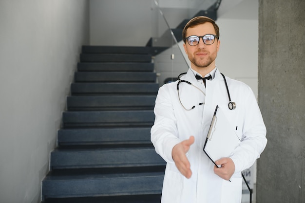 Retrato de un médico sonriente con uniforme de pie en el salón de la clínica de medicina