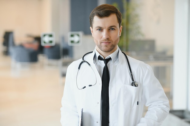 Retrato de un médico sonriente con uniforme de pie en el salón de la clínica de medicina