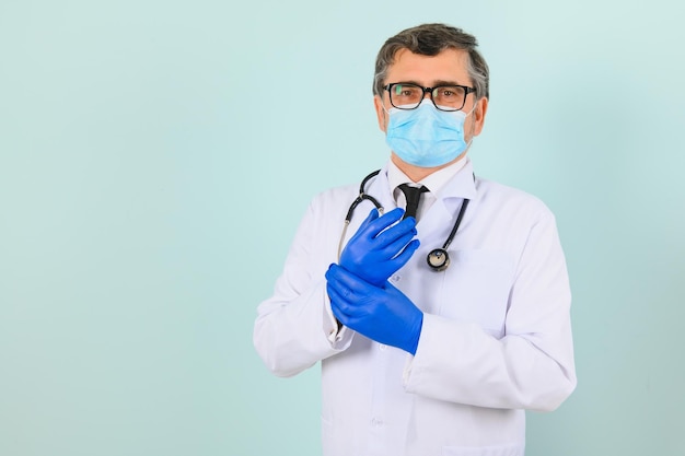 Retrato de un médico varón con una máscara y guantes sobre un fondo azul Concepto de atención médica