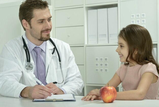 Retrato de médico varón con niña en la oficina del hospital