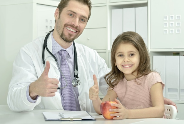 Retrato de médico varón con niña en la oficina del hospital