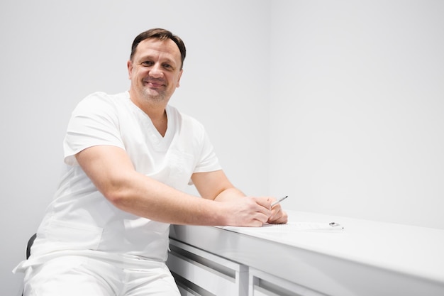 Retrato de un médico varón sentado en una mesa en la oficina