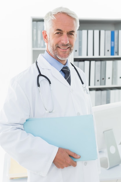 Foto retrato de un médico varón sonriente en el consultorio médico