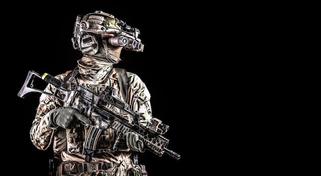 Retrato de medio cuerpo de fusilero de las fuerzas especiales del ejército, soldado de élite de comando equipado con auriculares tácticos de radio, rifle de servicio armado, usando gafas de visión nocturna en la oscuridad, aislado en negro, copyspace