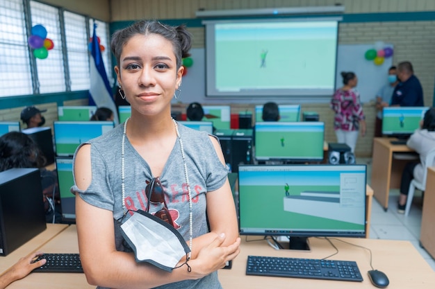 Retrato de medio cuerpo de una joven latina de América Central en un salón de clases lleno de computadoras