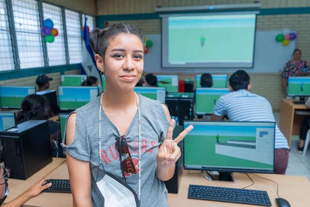 Retrato de medio cuerpo de una joven latina de Centroamérica haciendo un símbolo de paz en un salón de clases