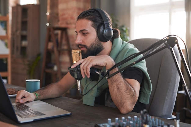 Retrato medio horizontal de un apuesto hombre barbudo que usa auriculares que comienzan a usar la transmisión en línea