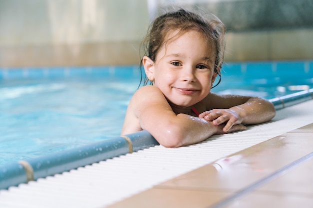 Retrato menina se divertindo na piscina interior. A menina está descansando no parque aquático.