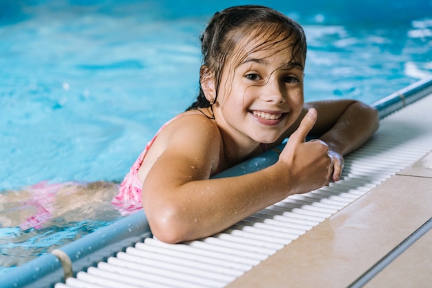 Retrato menina se divertindo na piscina interior. a menina está descansando no parque aquático.