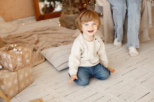 Retrato menino sentado no chão perto de presentes de natal