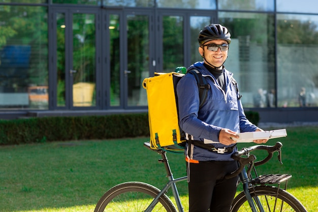 Retrato de mensajero de bicicleta con bolsa amarilla y bicicleta