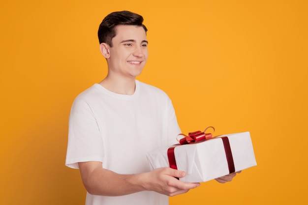 Retrato de mensajero de entrega chico mantenga caja de regalo grande dar sonrisa al cliente sobre fondo amarillo