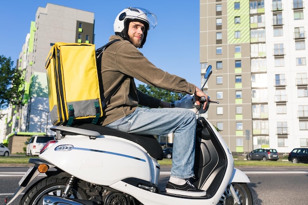 Retrato de un mensajero masculino en un scooter con una bolsa termo amarilla Entrega profesional de pedidos desde el restaurante