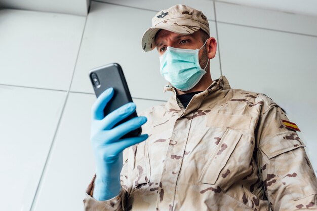 Retrato de un militar en máscara con smartphone