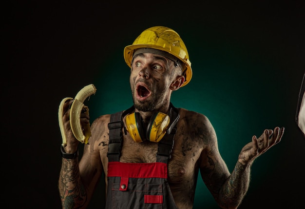 El retrato de un minero sonriente feliz comiendo un plátano para el almuerzo