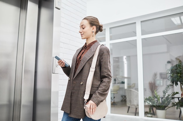 Retrato mínimo da cintura de uma jovem empresária esperando o elevador no prédio de escritórios moderno e