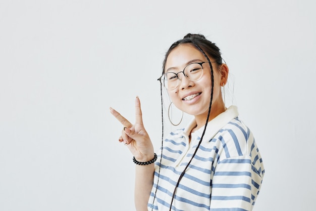 Retrato mínimo de adolescente asiática posando e olhando para a câmera contra um fundo branco, copie o espaço