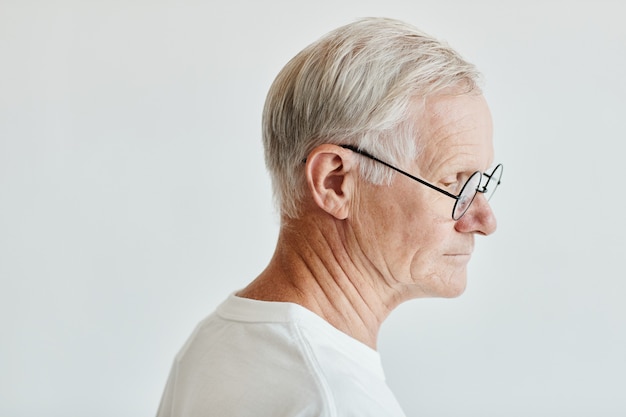Retrato mínimo de vista lateral de homem sênior de cabelos brancos em fundo branco, copie o espaço