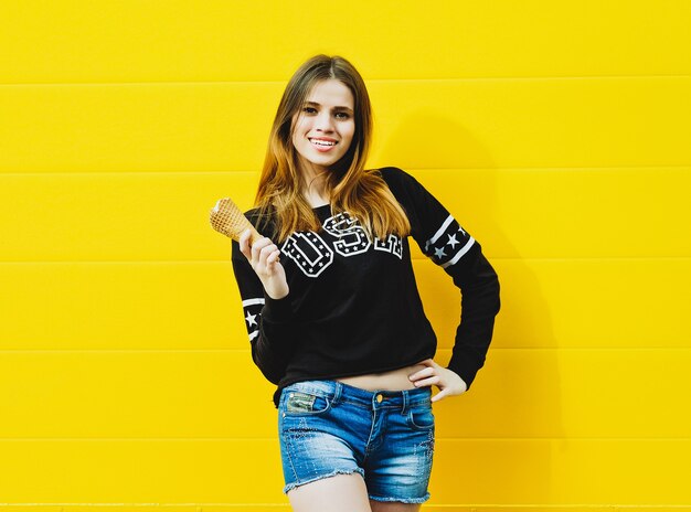 Retrato de moda al aire libre de chica joven inconformista con helado en amarillo