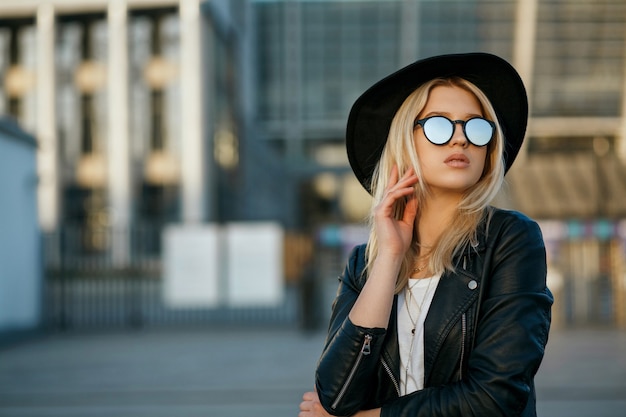 Retrato de moda al aire libre de una gloriosa mujer rubia con sombrero y gafas de sol de espejo. Espacio para texto