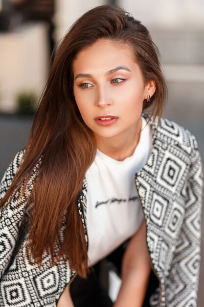 Retrato de moda de una bella mujer joven con una elegante chaqueta de bombardero en la ciudad