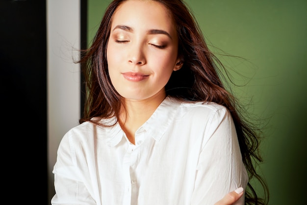 Retrato de la moda de la belleza de la mujer joven asiática sonriente sensual con el pelo largo oscuro en la camisa blanca en verde