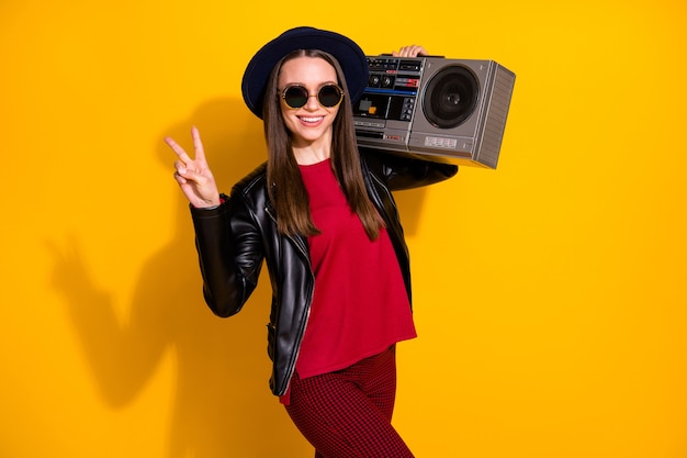 Foto retrato de moda chica alegre con boombox mostrando el signo de la victoria