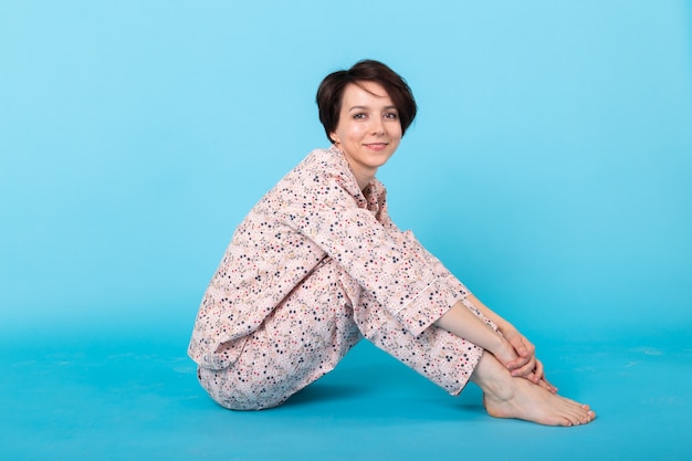 Retrato de moda chica muy guay en casa usar pijama divirtiéndose sobre fondo azul. Relájate bien