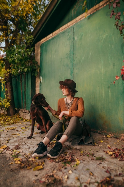 Retrato de moda de una dama sentada en el otoño en el suelo al fondo de la puerta verde