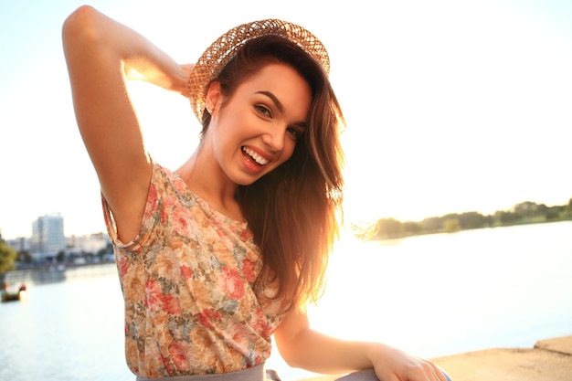 Retrato de moda de estilo de vida soleado de verano de mujer joven con estilo hipster. Mujer con dientes blancos pensando y mirando hacia los lados en un parque en verano