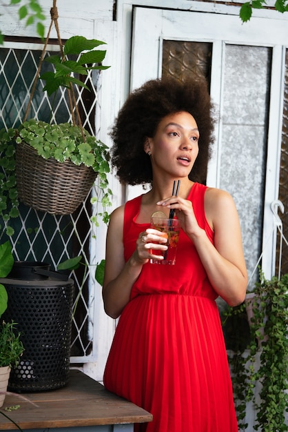 Retrato de moda de estilo de vida de verano de joven negra elegante con bebida