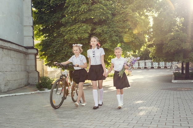 Retrato de moda feliz niños pequeños divirtiéndose con bicicleta en la ciudad.