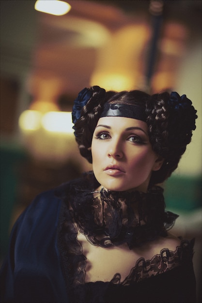 Foto retrato de moda de una hermosa morena con un vestido largo en el edificio de la antigua estación de tren. maquillaje creativo y peinado