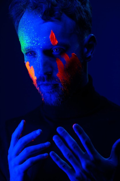 Retrato de moda Un hombre con pintura fluorescente en la cara bajo la luz de neón