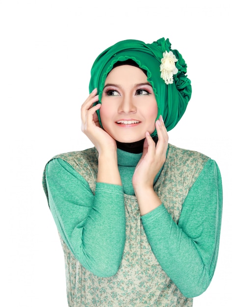 Retrato de moda de joven feliz hermosa mujer musulmana con traje verde vistiendo hijab y mirando hacia arriba