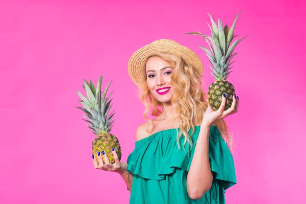 Retrato de moda joven hermosa mujer con piña sobre fondo rosa