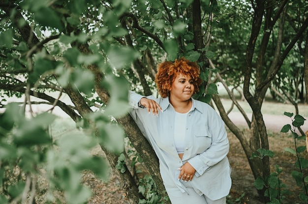 Retrato de moda de joven mujer afroamericana de talla grande naturalmente hermosa en traje de pantalón ligero