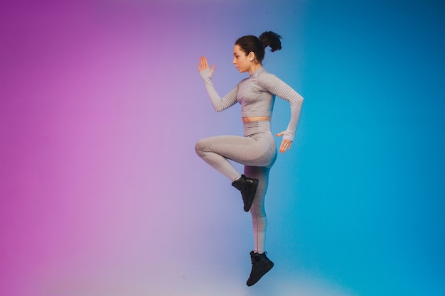 Retrato de moda de joven mujer caucásica en forma y deportiva sobre fondo degradado