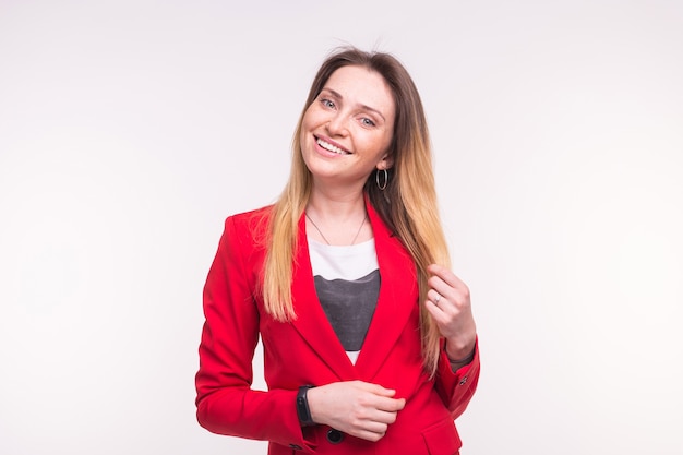 Retrato de moda joven mujer caucásica posando en traje rojo sobre fondo blanco.