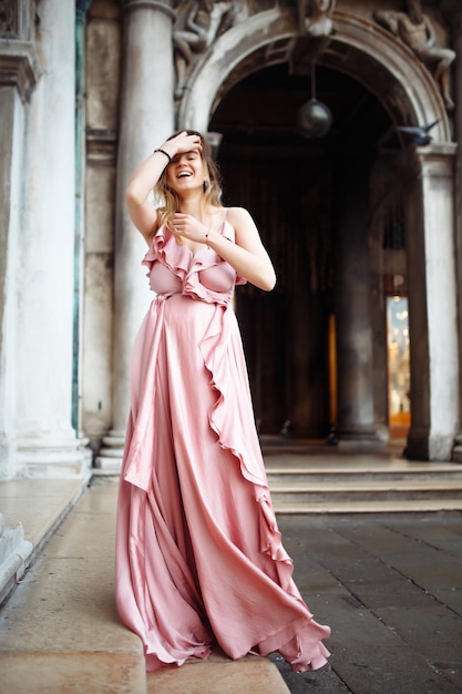 Foto retrato de moda de una mujer elegante con cabello rubio ondulado en un elegante vestido rosado concepto de estilo de moda