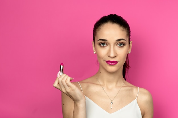 Retrato de moda de mujer hermosa con una cola de caballo sobre fondo rosa