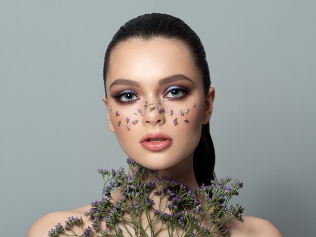 Retrato de moda de mujer hermosa joven con maquillaje floral de moda