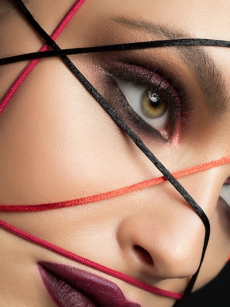 Foto retrato de moda de mujer hermosa joven con maquillaje de moda moderno de cerca. ojos y labios ahumados de color rojo oscuro.