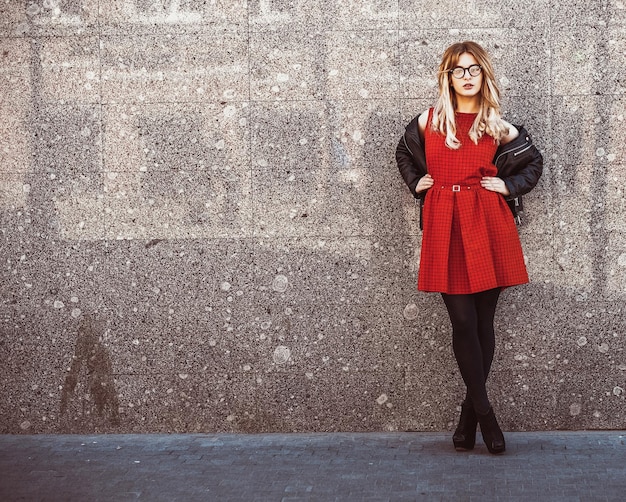 Retrato de moda de una mujer hipster con un elegante atuendo informal de verano posando contra el fondo de la pared.