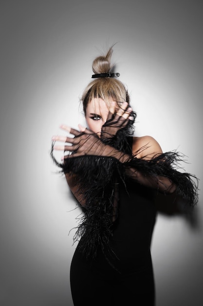 Retrato de moda de una mujer impresionante con largos guantes de tul con adornos de plumas en el estudio